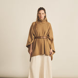 A woman look wearing an oversized camel turtleneck cashmere poncho with cut-sides, paired with white skirt | Angela | Linnea Lund