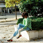 Black woman wearing Swedish clogs worn with off-white colored cashmere socks, blue jeans. and our Ursula sweater.