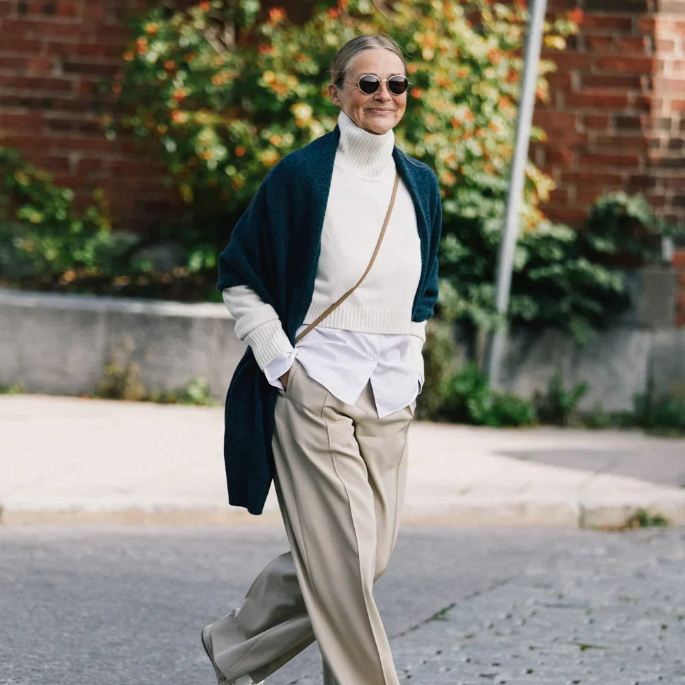 Sophie Lattes wearing an off-white cashmere turtleneck sweater with a Baltic blue cashmere shawl by Linnea Lund, walking confidently through the city streets.