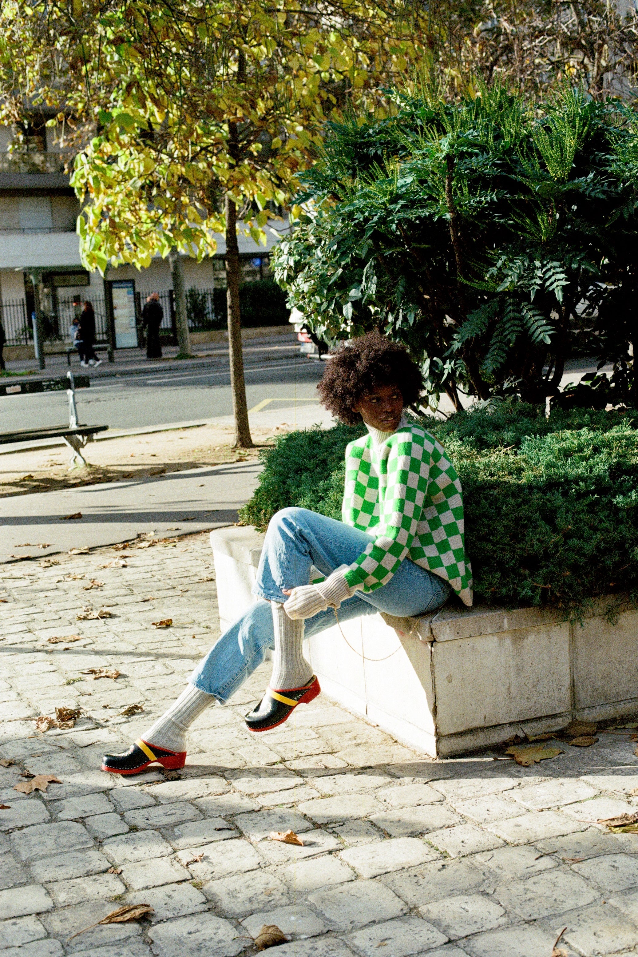 Black woman wearing Swedish clogs worn with off-white colored cashmere socks, blue jeans. and our Ursula sweater.
