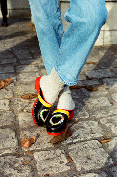 Swedish clogs worn with off-white colored cashmere socks and blue jeans.